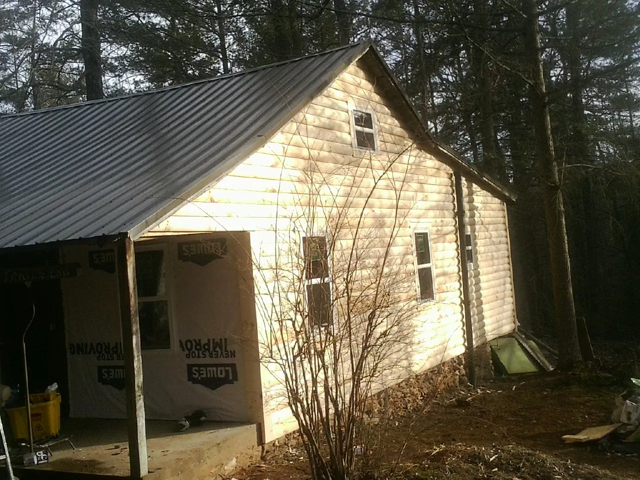 Log siding gable end under a dark metal roof edge in Indian Head