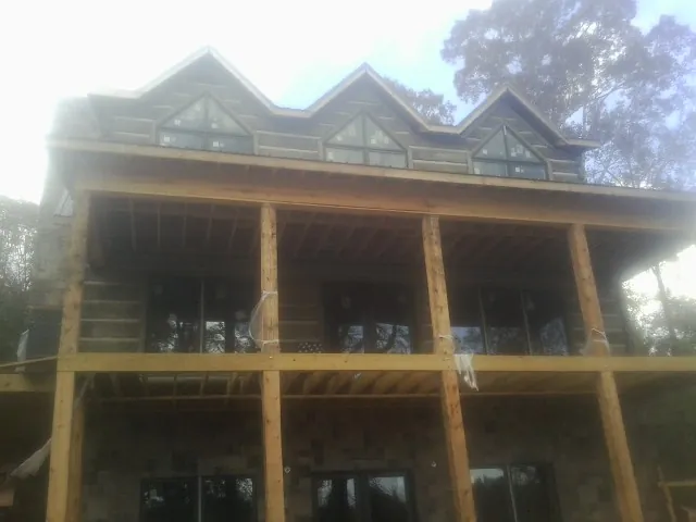 Dormers and porch framing on a large log home under construction — Roof Coating work by our crew in Indian Head