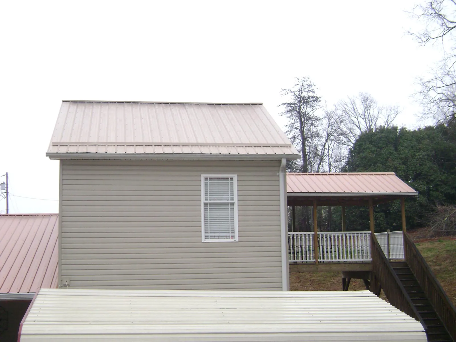 Tan metal roofs on a two story addition and attached porch, from a Roof Replacement job in Indian Head