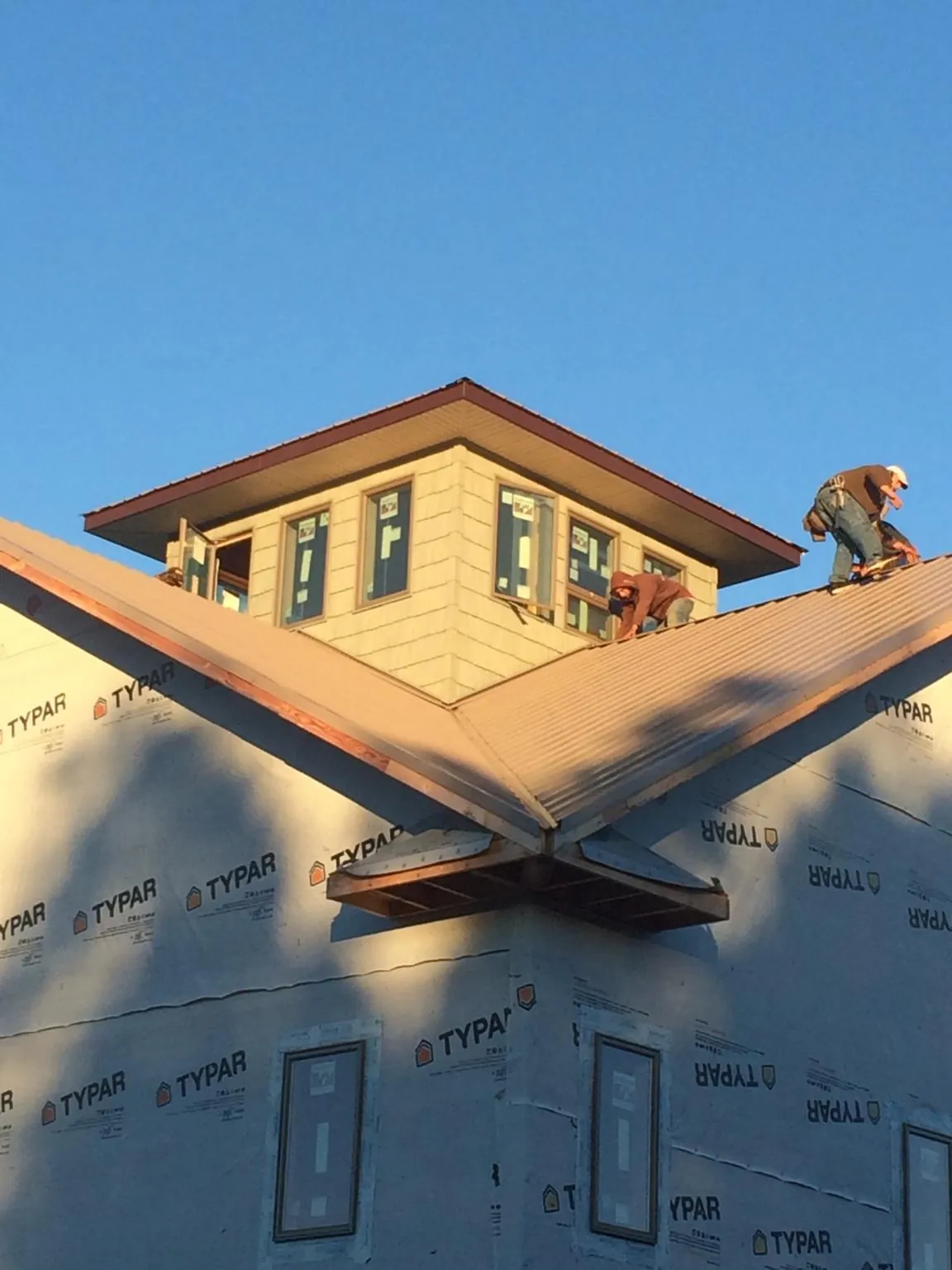 Roofers working around a rooftop cupola on a new metal roof at sunset — Roof Waterproofing in Indian Head by Roofing Brothers
